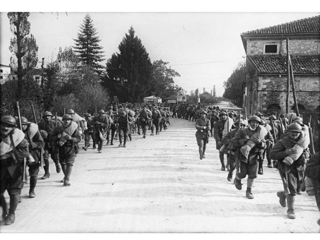 Italian troops marching two abreast either side of the road.
