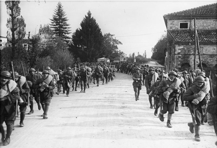 Italian troops marching two abreast either side of the road.